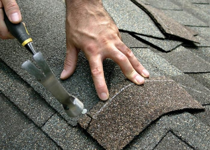 A close-up view of a person using a specialized tool to place shingles on a roof, representing expert craftsmanship by General Roofing Company in Oakland.
